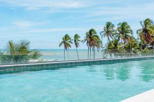 una piscina con palmeras y la playa en Condomínio Essence na Beira Mar de Tatuamunha, Rota dos Milagres, en Tatuamunha