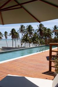 una piscina con palmeras en la playa en Condomínio Essence na Beira Mar de Tatuamunha, Rota dos Milagres, en Tatuamunha
