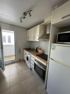 a kitchen with a white refrigerator and a dishwasher at Casa Gavendy, La Torre Golf Resort in Murcia