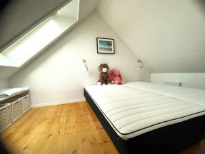 a bedroom with a bed with a teddy bear sitting on it at Byhus centralt på Læsø in Vesterø Havn