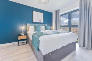 a bedroom with a large bed with a blue wall at Lovely 2 Bed Apartment Nightingale Quarter Derby in Derby