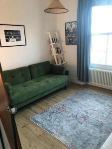 a living room with a green couch and a rug at 2 Bed Apt with air con - 10min to Canonbury Station in London