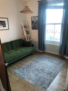 a living room with a green couch and a window at 2 Bed Apt with air con - 10min to Canonbury Station in London