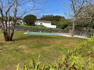 einen Garten mit einem Pool und einer Steinmauer in der Unterkunft Casa de Campo Franco da Serra in Angra do Heroísmo
