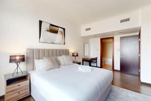 a bedroom with a large white bed and a desk at Turia Block A - Vacationer in Dubai