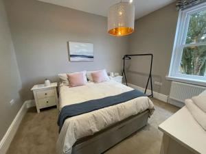 a bedroom with a bed with pink pillows on it at Nomi Homes * Budleigh Salterton*Beach* Sleeps 4 in Budleigh Salterton