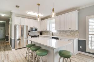a kitchen with white cabinets and green bar stools at Dolphin Harbor Orange Beach Condo w/ Beach Access! in Orange Beach