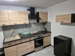 a kitchen with wooden cabinets and a black refrigerator at Pokoje KRASKA 36 in Łomża