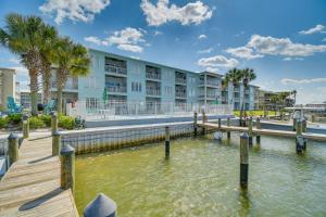 a building with a dock next to a body of water at Dolphin Harbor Orange Beach Condo w/ Beach Access! in Orange Beach