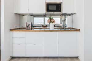 a kitchen with white cabinets and a microwave at Homeclub Apartment at Plaza Colon in Madrid