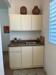 una cocina con armarios blancos y fregadero en Ache Pa Ti I Isabela, en Isabela