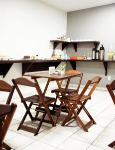 una mesa de madera y sillas en la cocina en Hotel Los Angeles Aeroporto, en Várzea Grande