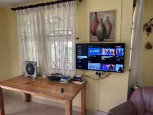 a room with a wooden table and a television at Beau seaside villa in Flic-en-Flac