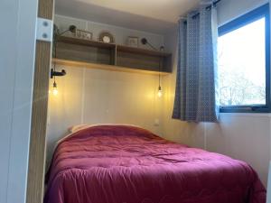 um quarto com uma cama rosa num quarto com uma janela em Camping pays de Beille em Les Cabannes