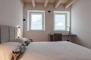 1 Schlafzimmer mit einem Bett, einem Schreibtisch und 2 Fenstern in der Unterkunft COMFORT 70 in Levico Terme