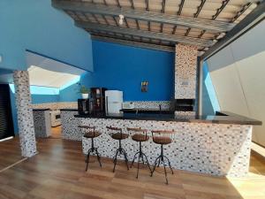 a kitchen with a bar with stools and a blue wall at Espaço céu Azul in Ribeirão Preto
