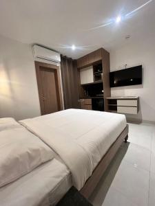 a bedroom with a large white bed and a flat screen tv at NOVAPARK FERROVIARIA in Guayaquil