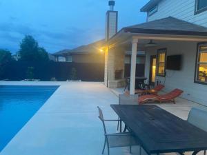 a pool with a table and chairs next to a house at Lxry 4 BR Bckyd, Pool, Hot Tub near attrctns (Tal.) in Helotes