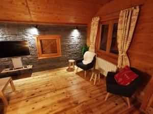 The dream catcher -Spa- panoramic sauna- 2 MINUTES FROM THE SLOPES في لابريس: غرفة معيشة مع أرضيات خشبية وتلفزيون وكراسي