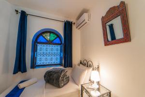 1 dormitorio con 1 cama con ventana y espejo en DAR NOKHBA INN, en Chefchaouen