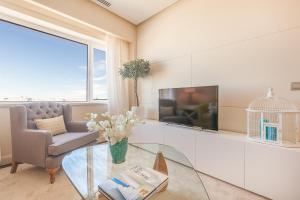 a living room with a tv and a chair and a glass table at Homeclub Exclusive Flat at Madrid Tower in Madrid