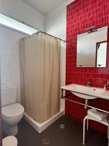 een badkamer met een toilet, een wastafel en rode tegels bij Residência Aviz in Peniche