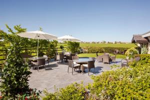 a patio with tables and chairs and umbrellas at Wrightington Hotel & Health Club in Wigan