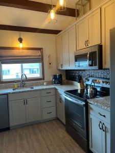 a kitchen with white cabinets and a stove top oven at Fun on Moosehead Lake in Greenville Junction