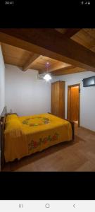 um quarto com uma cama com um cobertor amarelo em B&B A CASA DI MARIO em San Severino Lucano