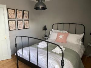 ein Schlafzimmer mit einem schwarzen Bett und einem rosa Kissen in der Unterkunft Charming Bight Cottage moments from beach by Whitstable-Holidays in Whitstable