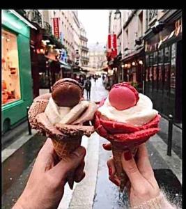duas pessoas a segurar cones de gelado numa rua em St Michel studio em Paris