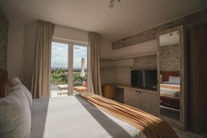 um quarto de hotel com uma cama, uma televisão e uma varanda em Chozos Resort em Agrelo