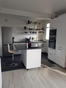 a kitchen with white cabinets and a chair in it at Chambre Céleste in Tours