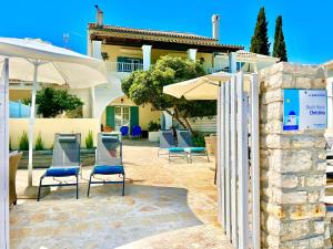a group of chairs and umbrellas in front of a house at Beachfront House Christina with private heatable pool by DadoVillas in Kassiopi