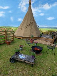 namiot teepee ze stołem, krzesłami i sprzętem do grillowania w obiekcie Burtree Country House and Retreats Tipi w mieście Thirkleby