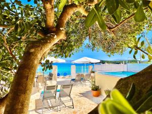 a view of a beach with chairs and a swimming pool at Beachfront House Christina with private heatable pool by DadoVillas in Kassiopi