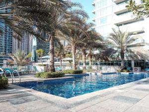 a swimming pool with palm trees and a building at Frank Porter - Al Majara 2 in Dubai