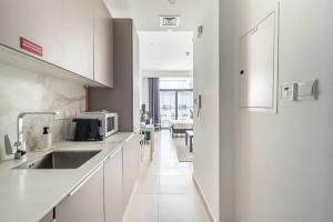 a white kitchen with a sink and a microwave at Frank Porter - Divine Residences in Dubai