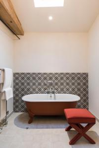 a bathroom with a bath tub and a red stool at Les Clefs de Troplong Mondot in Saint-Émilion +27 photos
