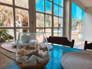 een glazen vaas gevuld met schelpen op een tafel bij IBELLO BEACH Pousada in Cabo Frio
