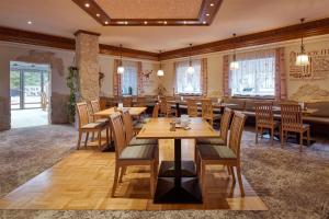 un restaurante con mesas y sillas de madera y ventanas en Hotel Ladenmühle, en Kurort Altenberg