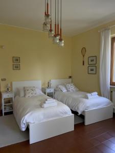 two white beds in a room with yellow walls at La Casa del Bosco - Villa con vista panoramica su Bobbio e la Val Trebbia in Bobbio