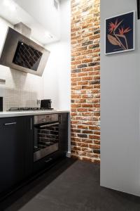 uma cozinha com um fogão e uma parede de tijolos em Househost Apartment: Józefa 2/10 em Cracóvia