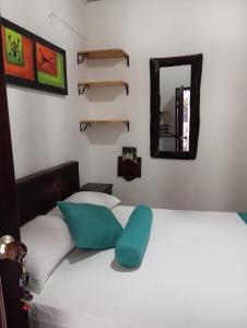 a white bed with a blue pillow and a mirror at SANTANDER ALEMAN HOSTEL in San Gil