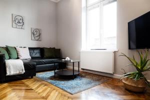 uma sala de estar com um sofá preto e uma mesa em Househost Apartment: Józefa 2/10 em Cracóvia
