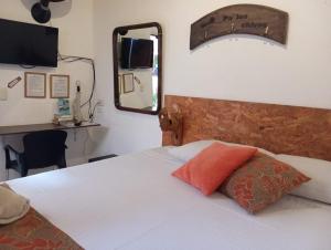 um quarto com uma cama branca e um espelho em SANTANDER ALEMAN HOSTEL em San Gil