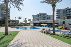einem Pool mit Palmen vor einem Gebäude in der Unterkunft Frank Porter - MAG 560 in Dubai
