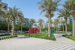 a park with palm trees and red sculptures in front of a building at Frank Porter - MAG 560 in Dubai