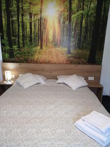 a bed with a painting of a forest at Casa Liana in Buşteni