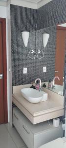 La salle de bains est pourvue d'un lavabo avec deux robinets et un miroir. dans l'établissement Quarto Centro Dourados, à Dourados